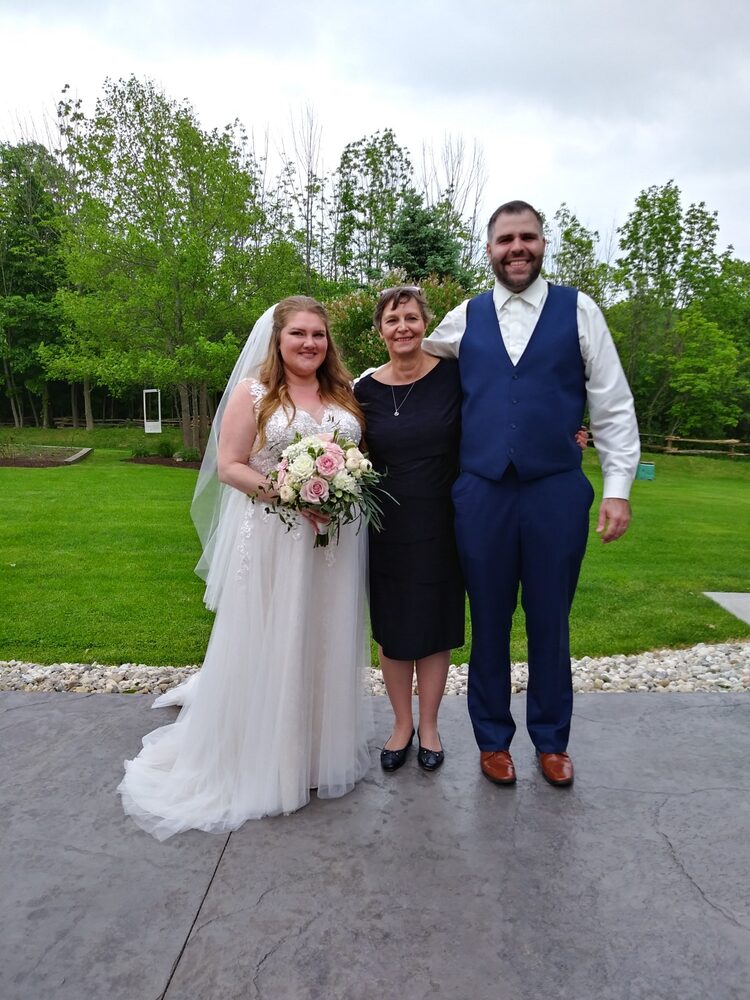 Debra standing with a newly married couple outdoors