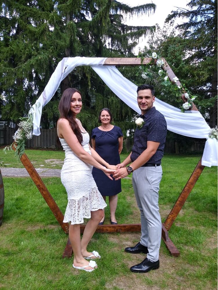 Debra with a newly married couple beneath an outdoor arch
