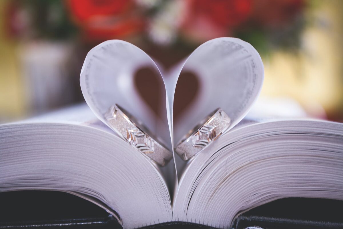 Wedding rings arranged in a heart shape on an open book